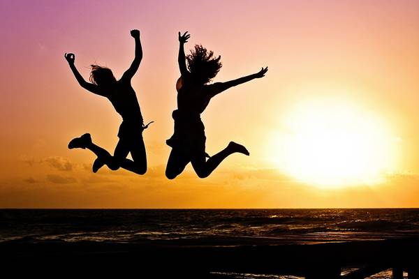 zwei Freunde springen beim Sonnenuntergang in die Luft